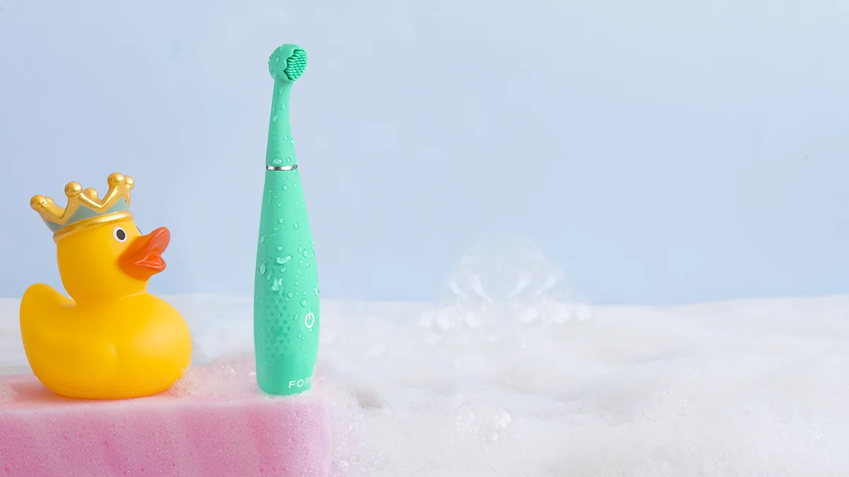 issa 4 baby electric toothbursh for baby next to a yellow rubber ducky